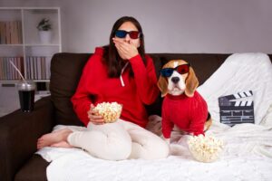 A young girl with her dog beagle in 3 d glasses watching a movie at home